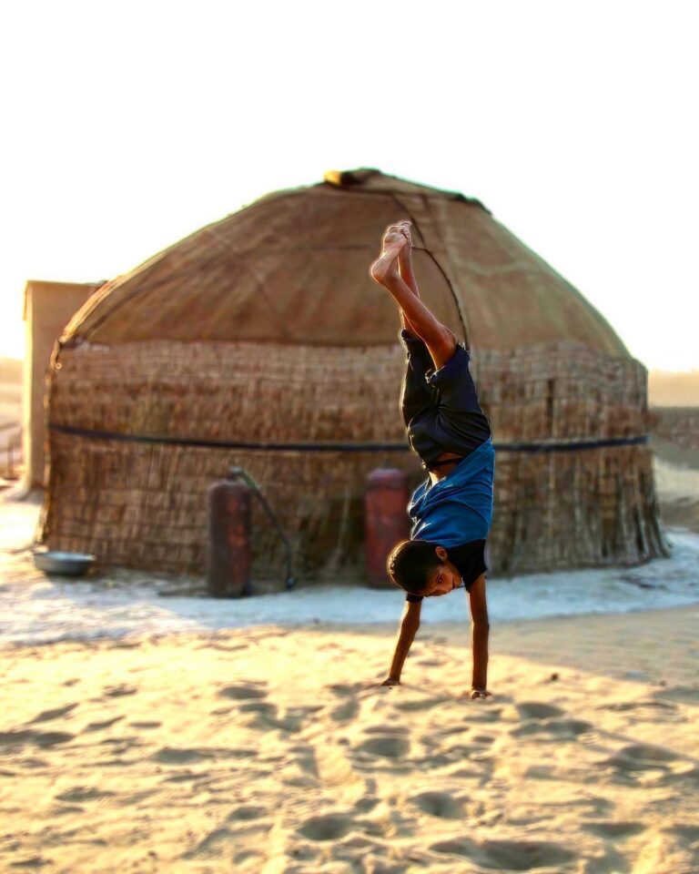 Kid showing off in front of his yurt, in the oasis of Yerbent, in the middle of the Karakum desert, in…